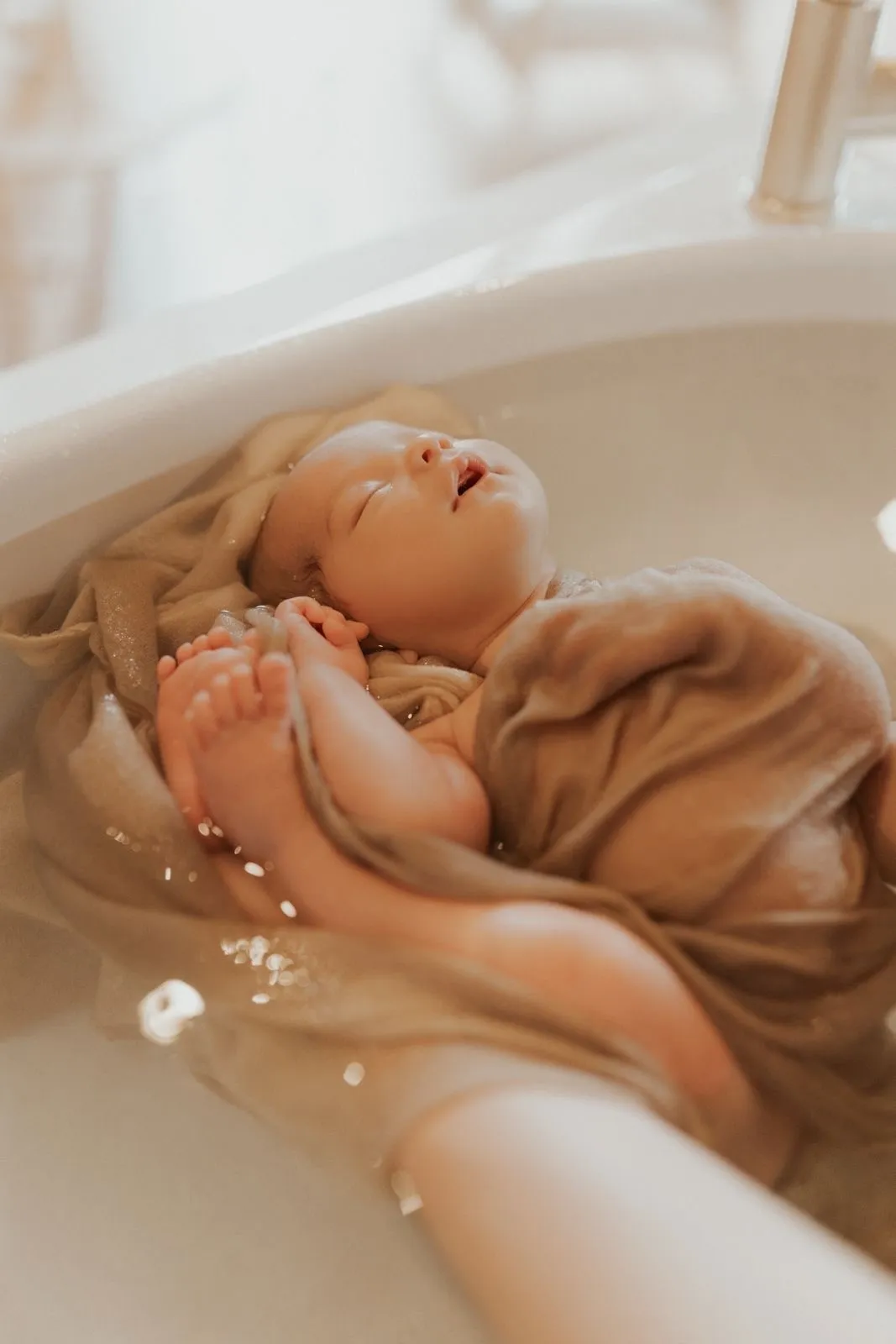 Nouveau-né endormi enveloppé dans un lange, flottant dans l'eau du bain