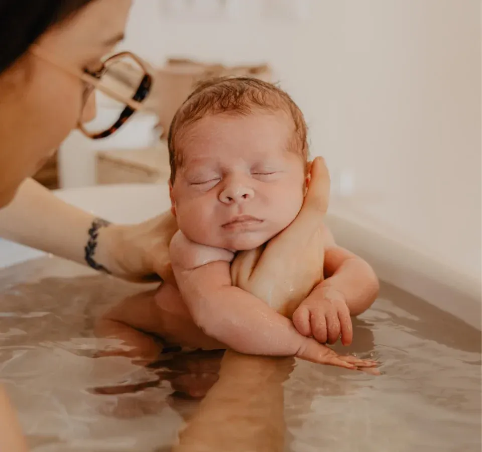 Laury Goncalves, fondatrice de l'Institut Périnatal, tenant un nouveau-né dans son bain d'accueil