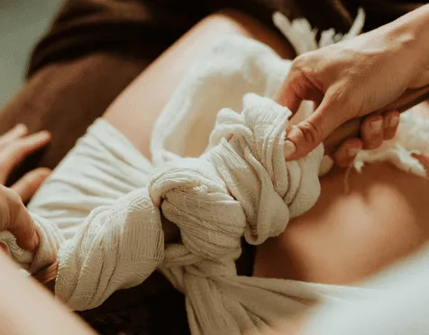 Nœud de rebozo noué sur le ventre lors d'un soin de fermeture du postpartum
