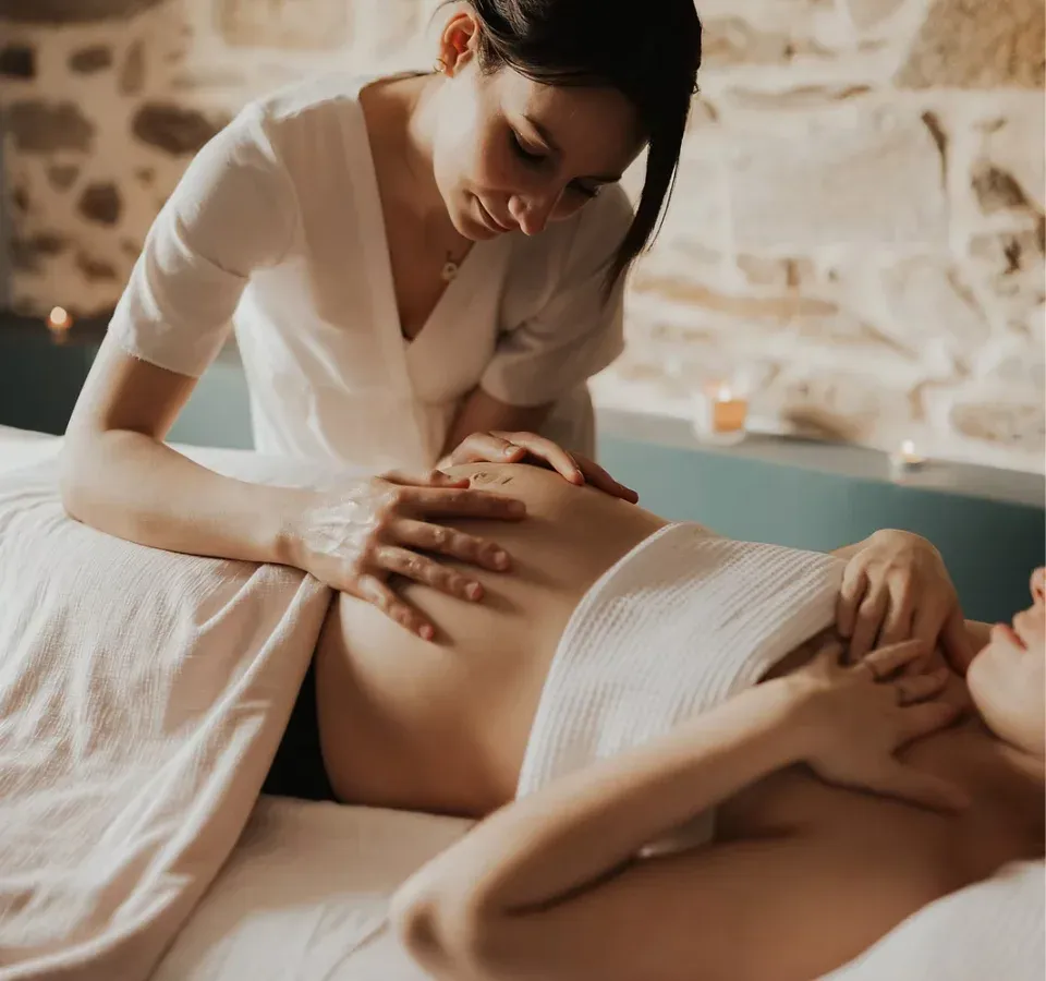 Praticienne massant le ventre d'une femme enceinte allongée